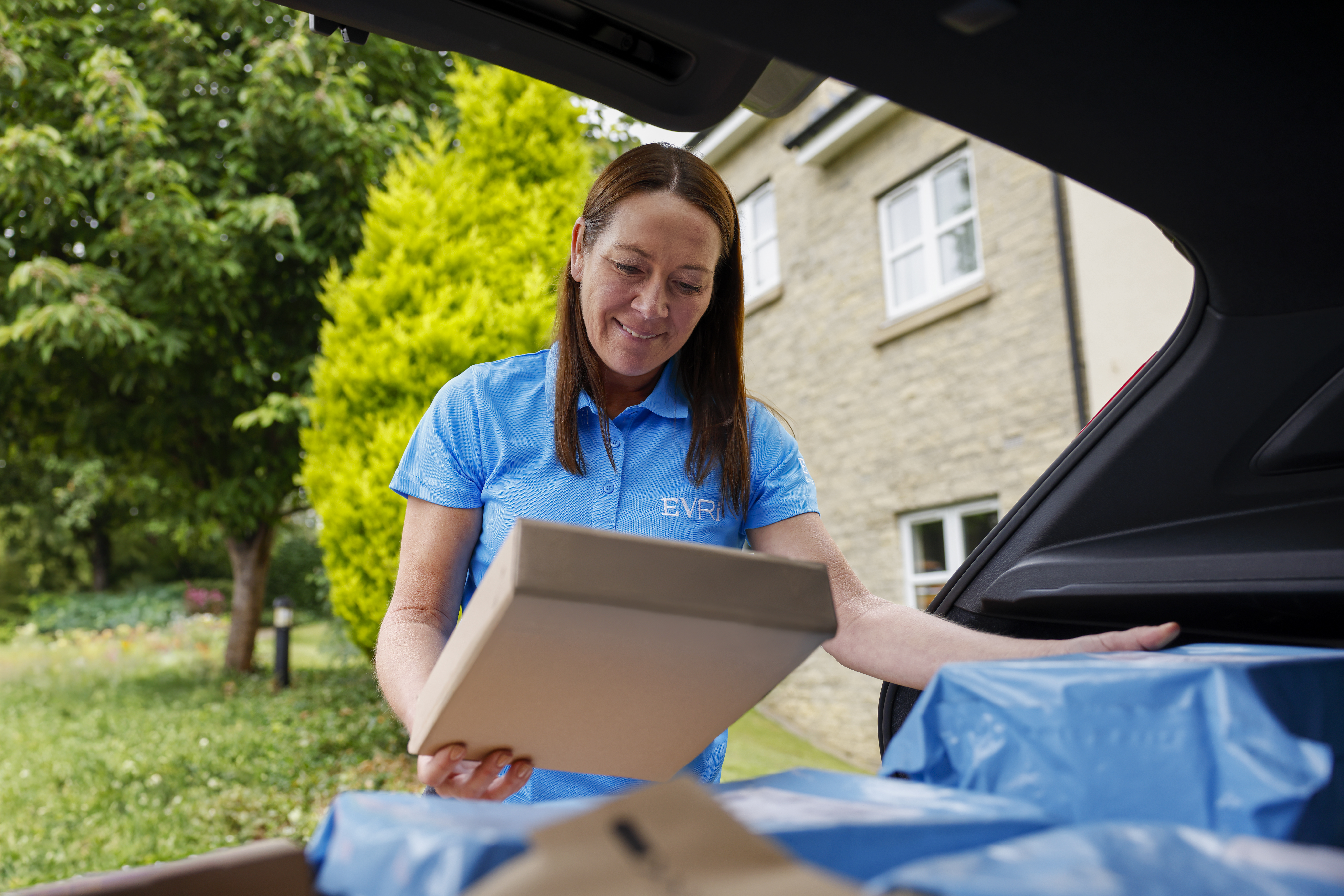 An Evri Courier checking the label on a parcel at their car before delivering