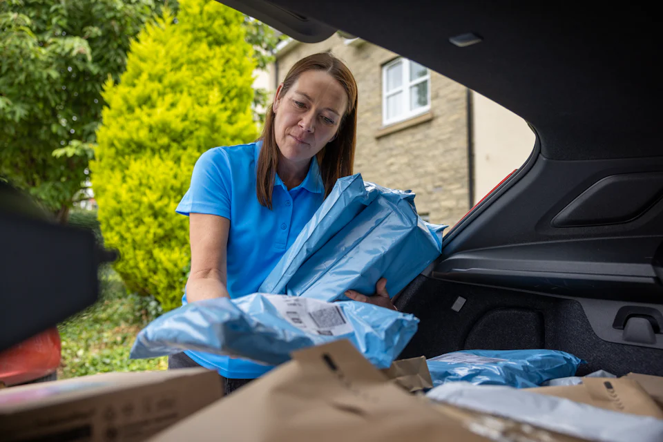 An Evri Courier gathering multiple parcels from their car to deliver to their destination