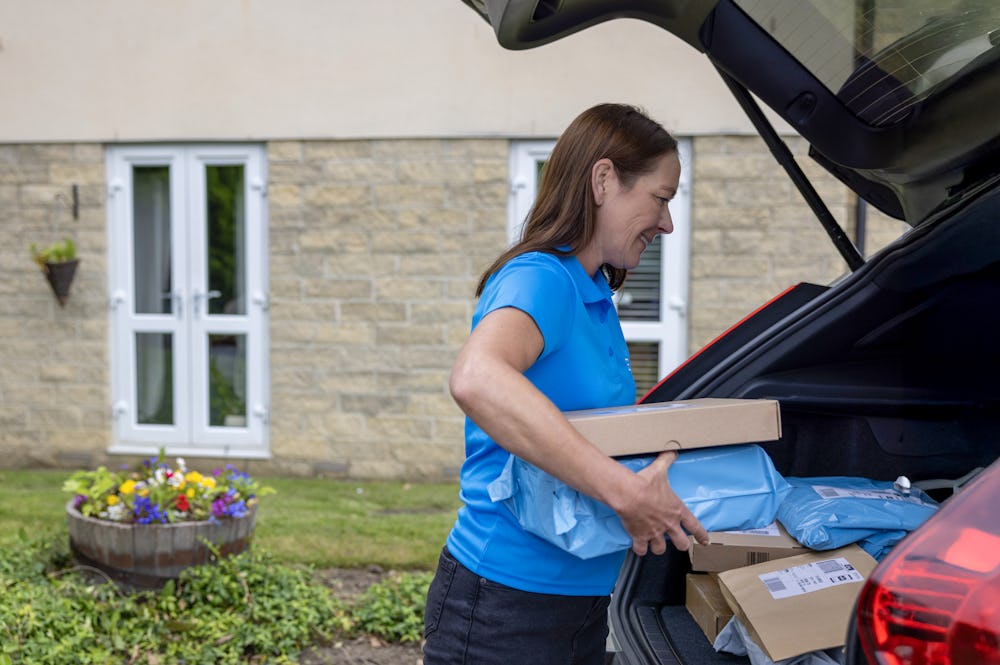 An Evri Courier gathering multiple parcels from their car to deliver to their destination