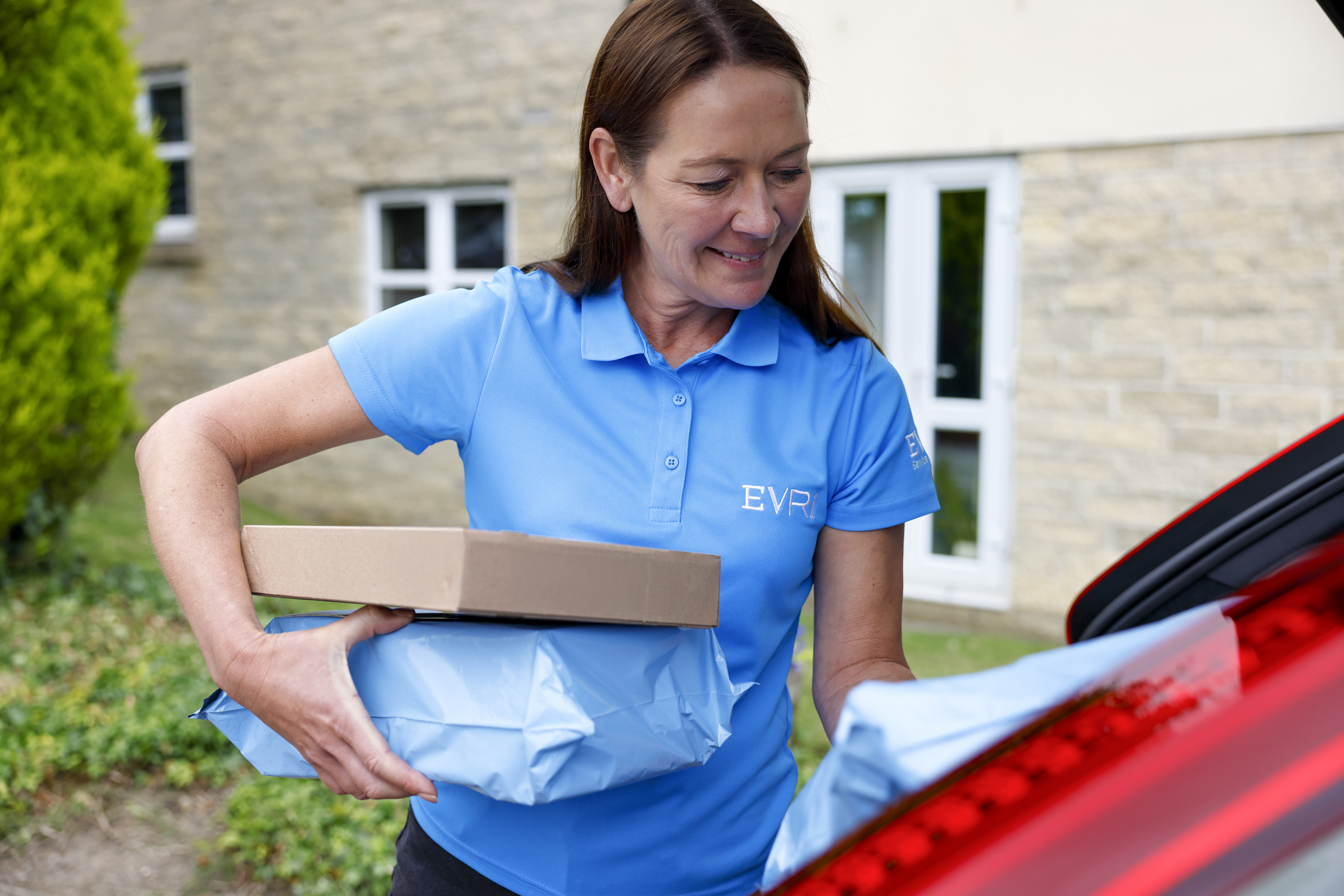 An Evri Courier gathering multiple parcels from their car to deliver to their destination