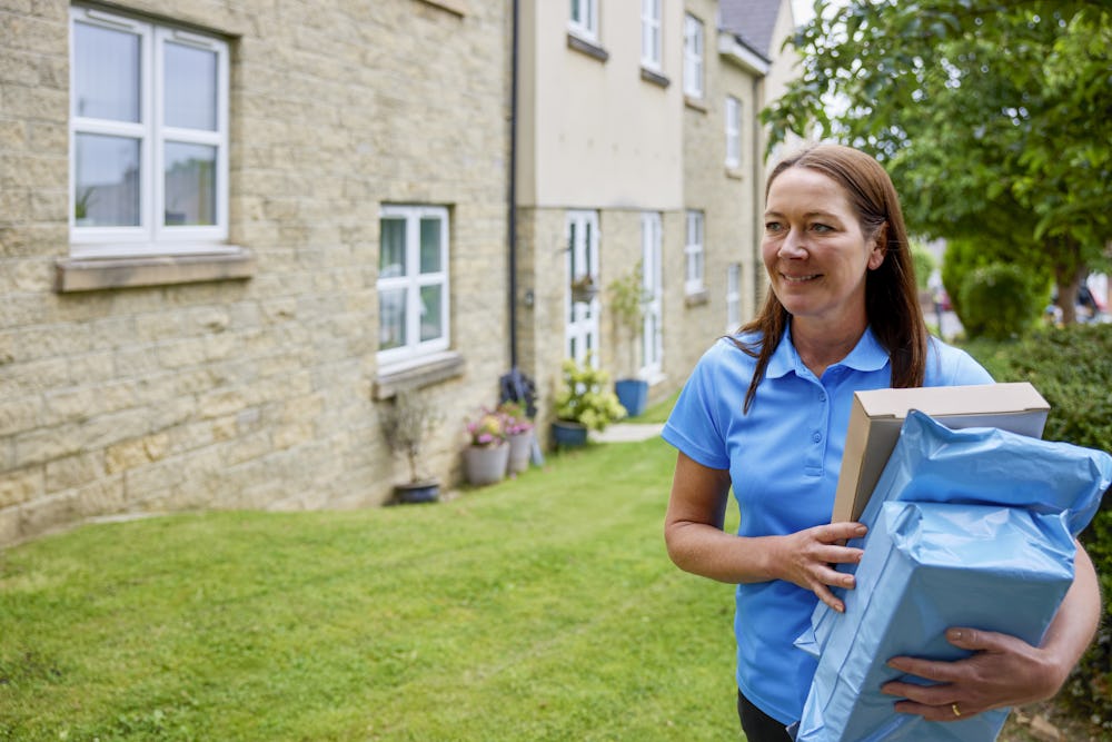 An Evri Courier carrying multiple parcels to their destination in a residential area