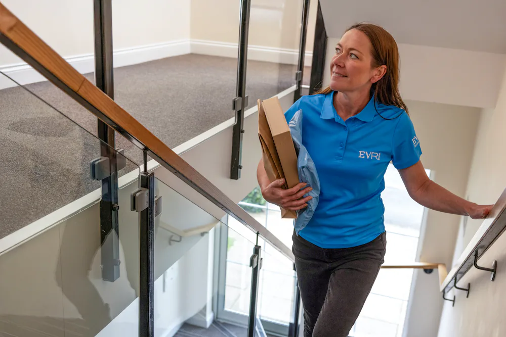 An Evri Courier climbing the stairs in a block of flats to deliver a parcel to a customers door