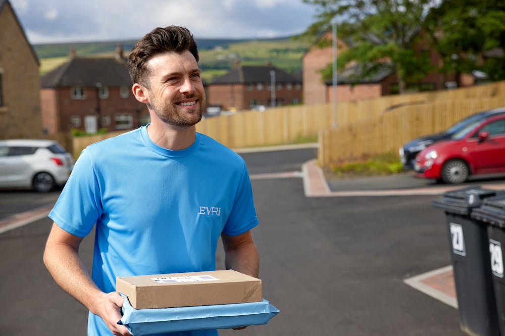 An Evri Courier walking down the street in a residential area carrying two parcels