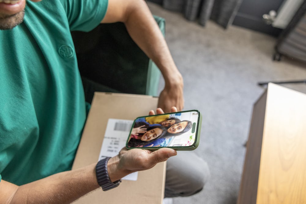Top down view of a man with a parcel on his lap watching an Evri video. The video is of a mother and two children smiling and waving.