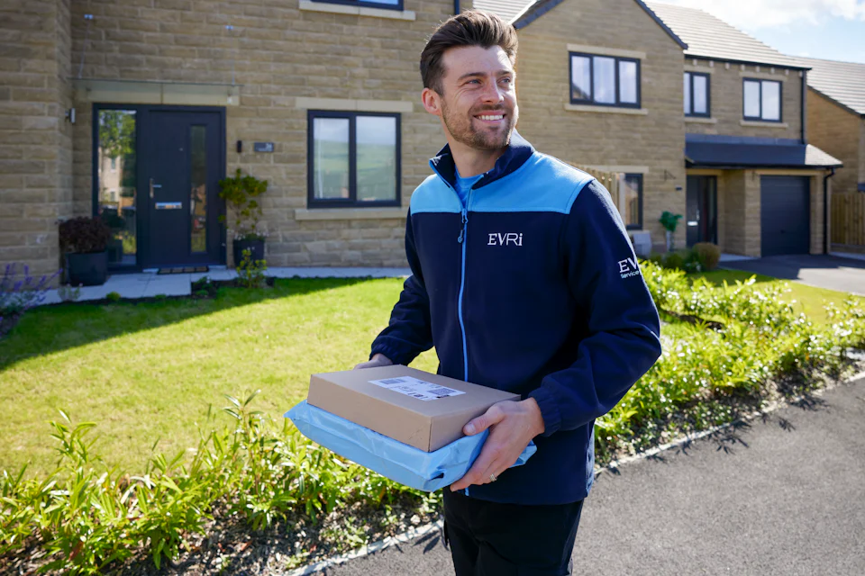 An Evri Courier walking down the street in a residential area carrying two parcels