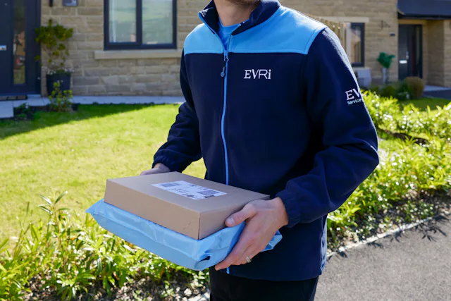 An Evri Courier walking down the street in a residential area carrying two parcels