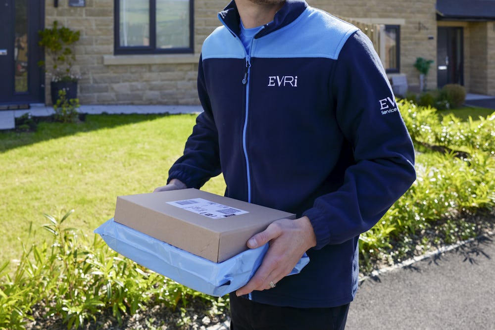 An Evri Courier walking down the street in a residential area carrying two parcels