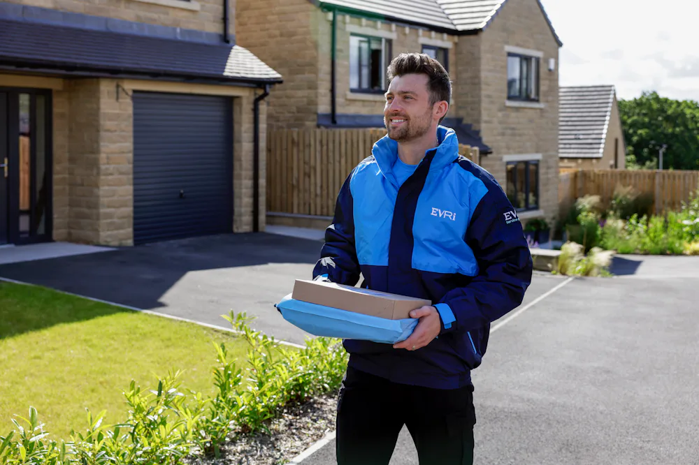 An Evri Courier approaching the driveway of a suburban house carrying two parcels