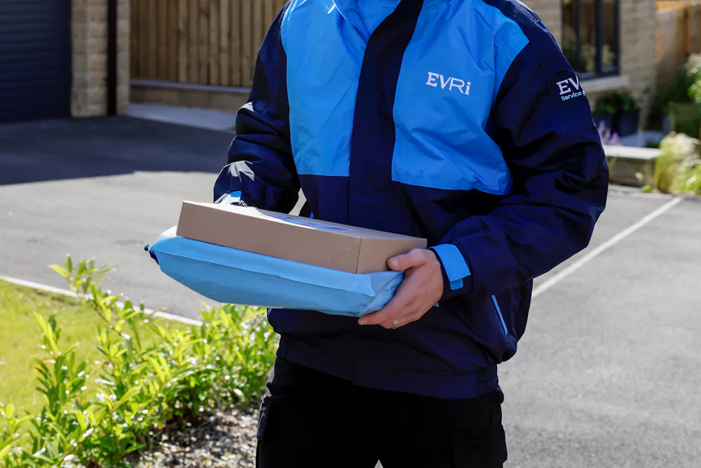 An Evri Courier approaching the driveway of a suburban house carrying two parcels