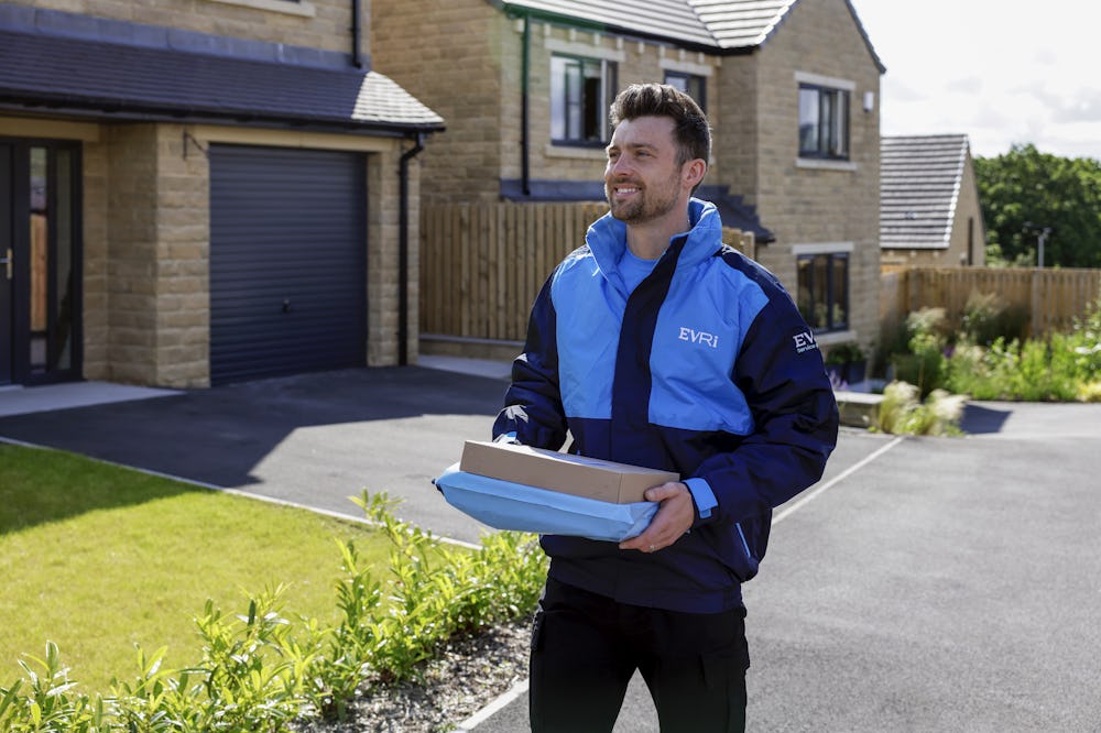 An Evri Courier approaching the driveway of a suburban house carrying two parcels