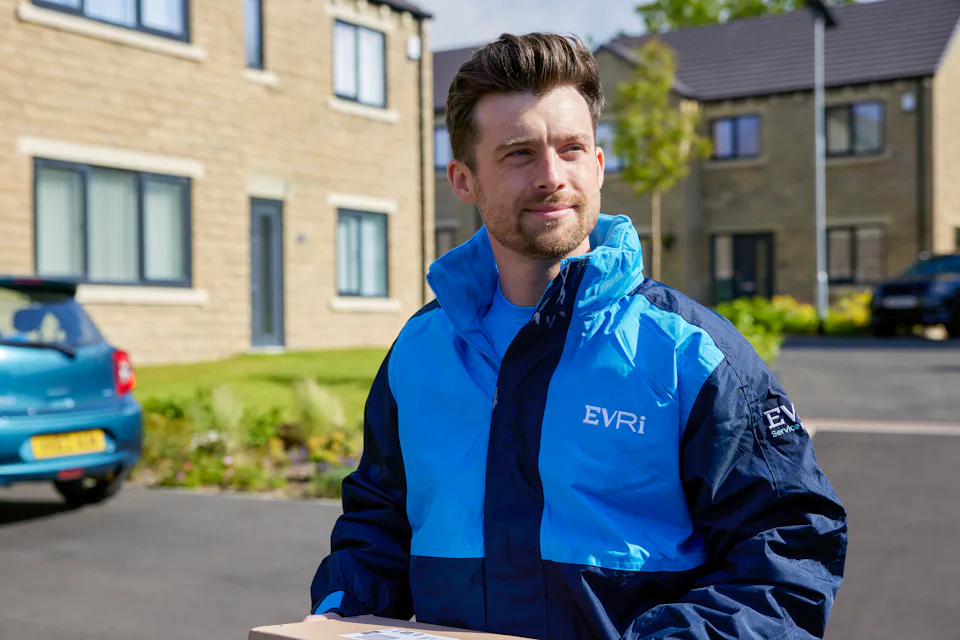 An Evri Courier walking down the street in a residential area carrying parcels