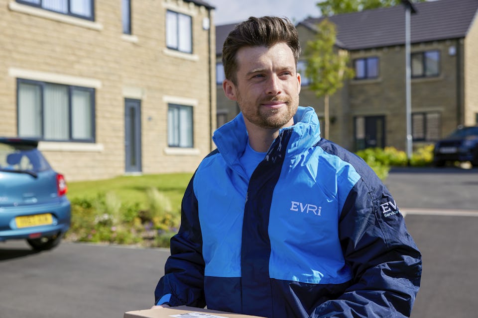 An Evri Courier walking down the street in a residential area carrying parcels
