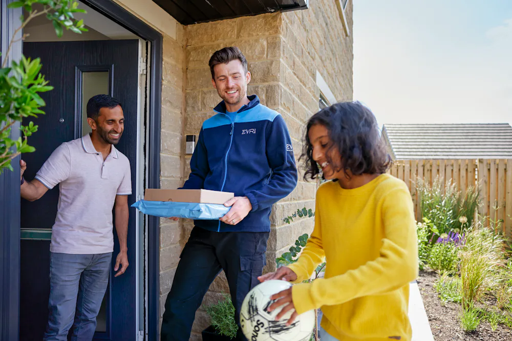 An Evri Courier about to deliver two parcels, and a customer ready to recieve them are being entertained by a child with a football.