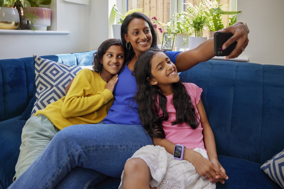 A mother and her two children record an Evri video on their mobile device. They are sat cuddled up on a sofa in their living room.