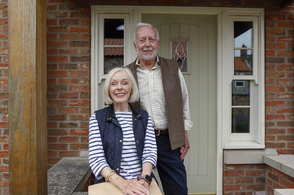 An older couple pose on their doorstep with their parcel after an Evri delivery.