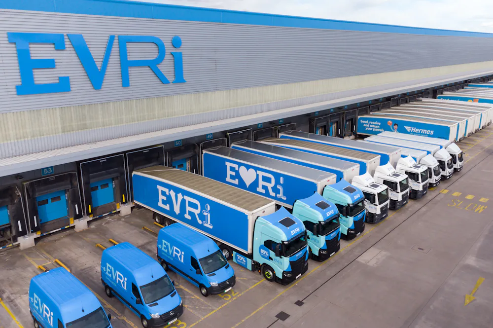 A drone shot of an Evri hub. There are rows of Evri trucks and vans of various sizes stationed at the units across the hub ready to take on parcels.