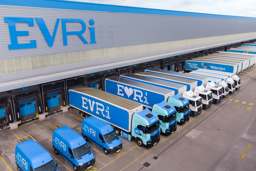 A drone shot of an Evri hub. There are rows of Evri trucks and vans of various sizes stationed at the units across the hub ready to take on parcels.