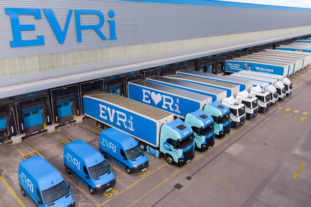 A drone shot of an Evri hub. There are rows of Evri trucks and vans of various sizes stationed at the units across the hub ready to take on parcels.