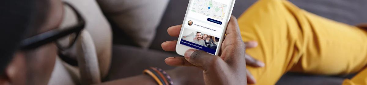 Customer looking down at their mobile with the display showing their tracking notification in full view