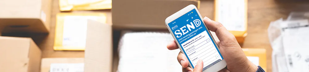 A close-up bird's eye view of a customer holding their mobile phone shows the Evri website home page on display. Lots of parcel boxes can be seen in the background.