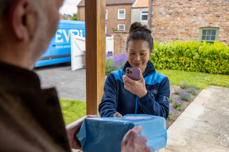 Evri courier delivers and scans a parcel for a customer who is accepting the parcel on their doorstep
