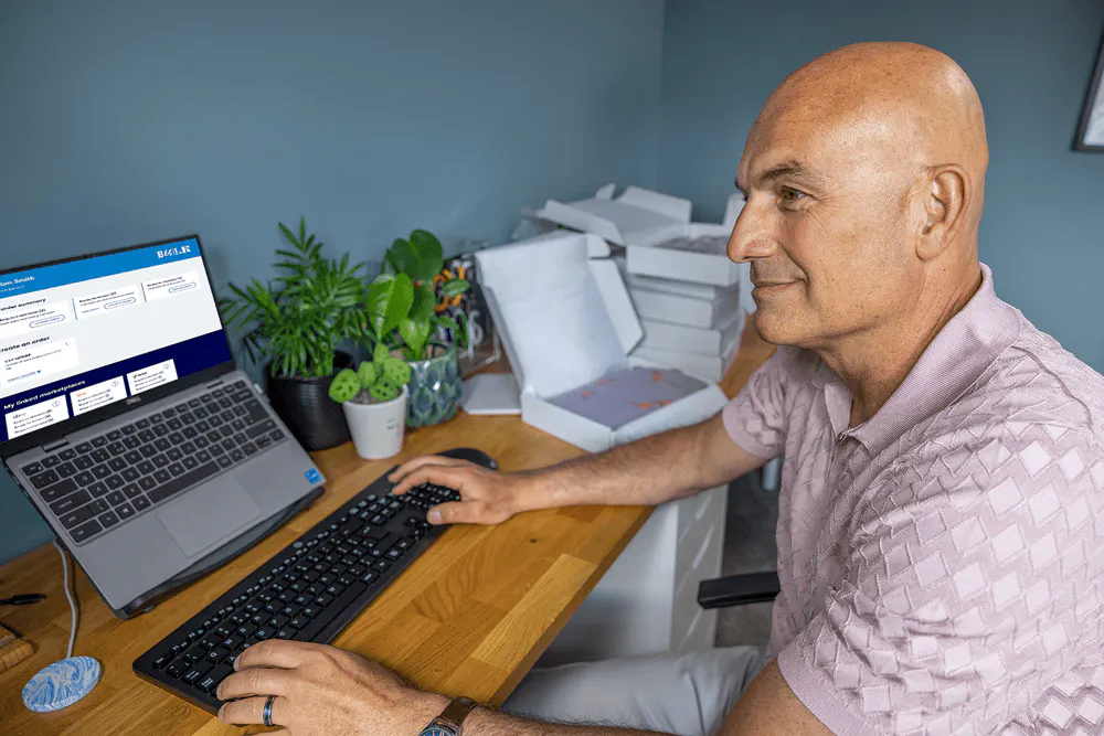Business owner sat at a desk in their home office using their laptop to book multiple parcels