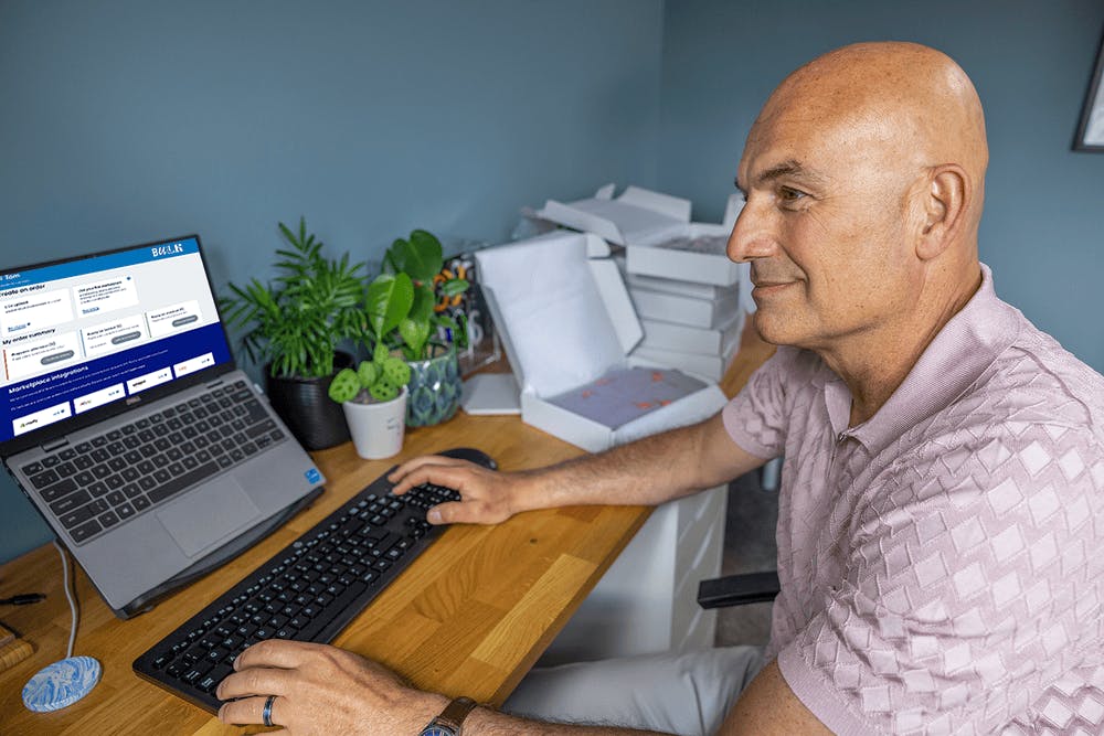 Business owner sat at a desk in their home office using their laptop to book multiple parcels