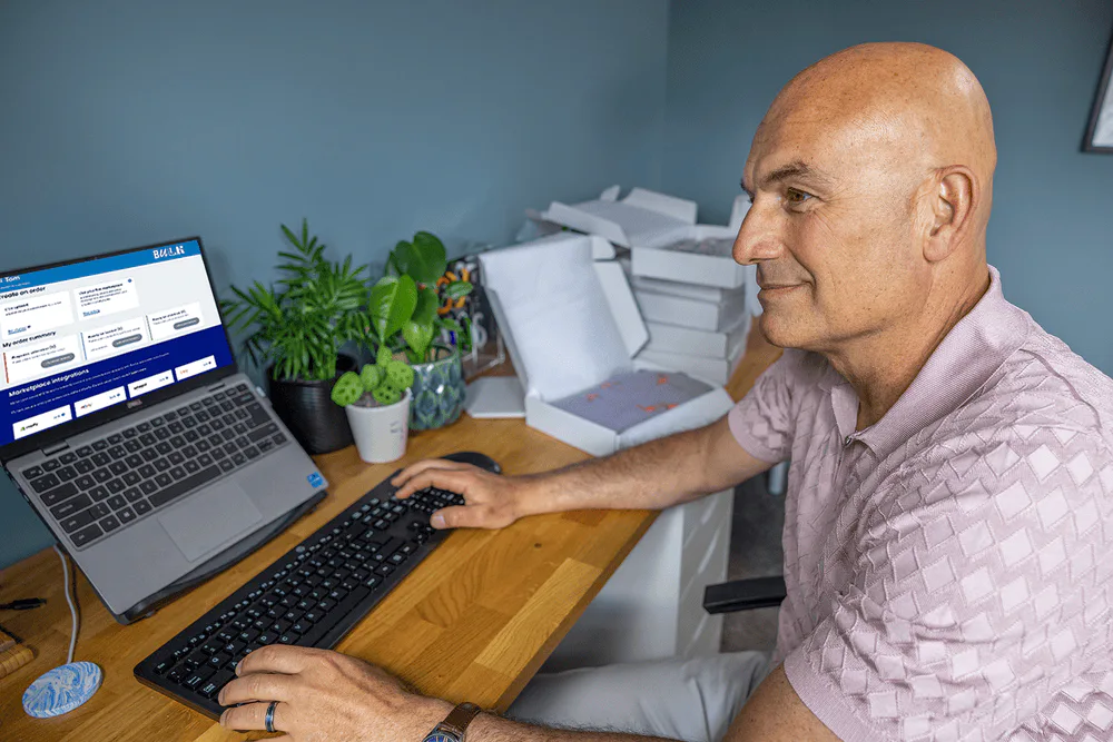 Business owner sat at a desk in their home office using their laptop to book multiple parcels