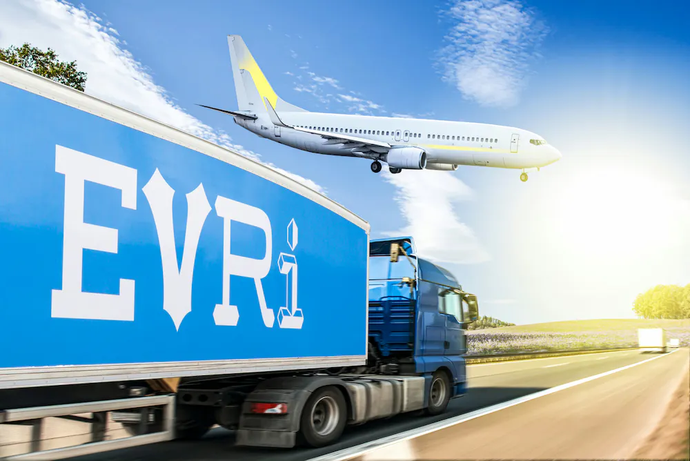 A side profile view shows an Evri-branded lorry is driving along a straight road with an aeroplane that can be seen closely above.
