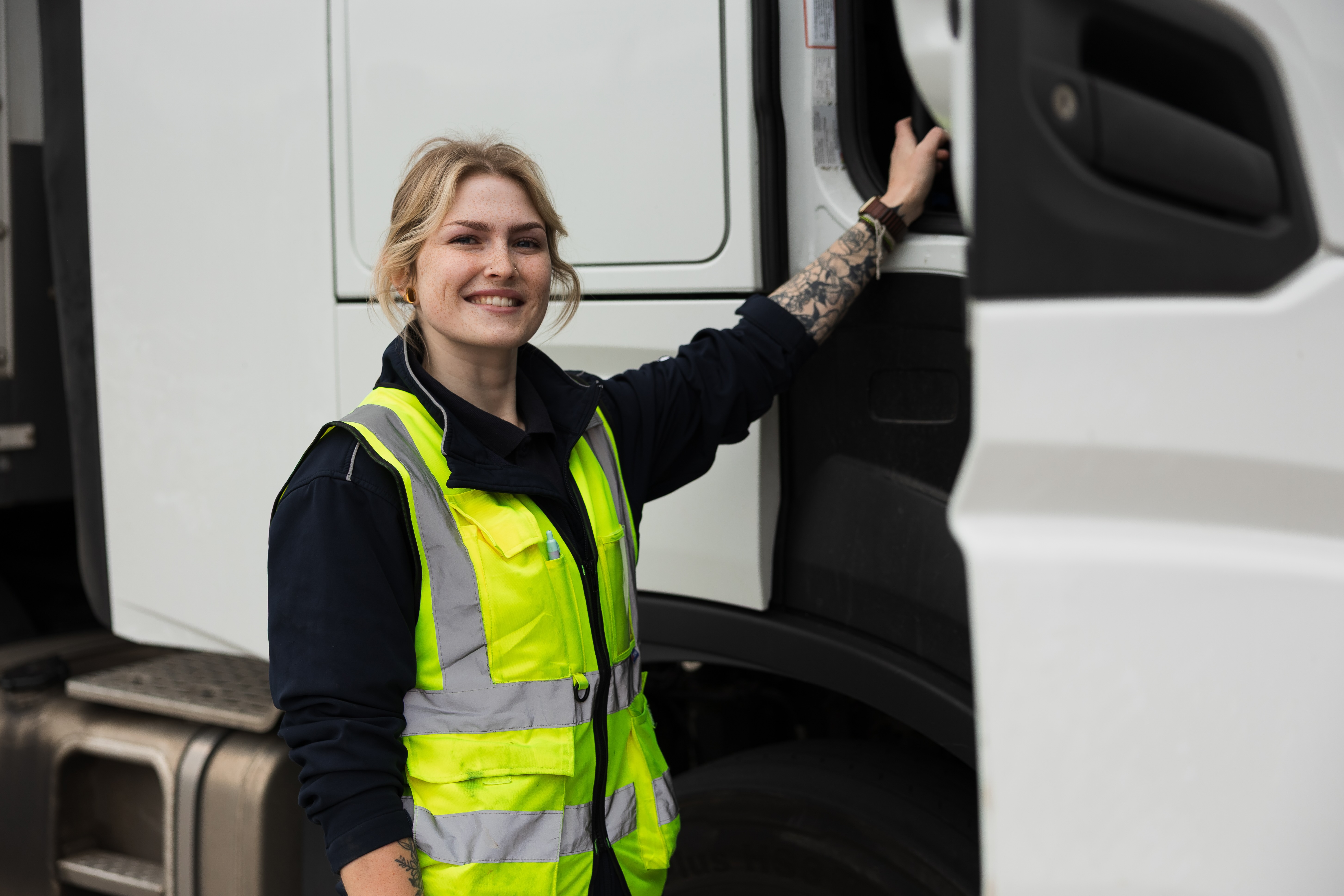 A female HGV driver poses alongside the cab of her HGV