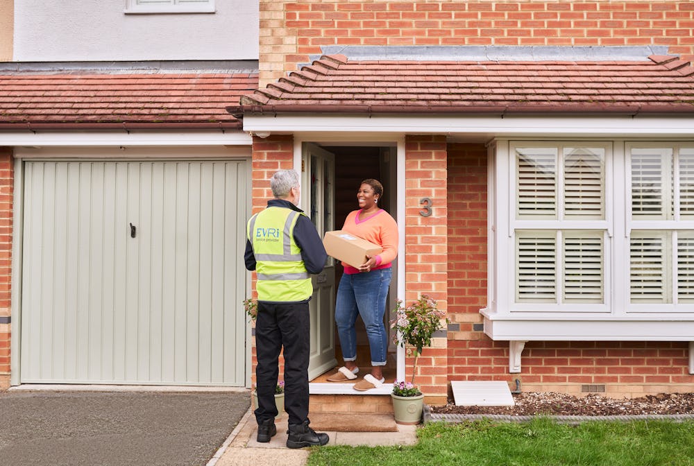woman stood at front door holding box and speaking to courier in high visibility jacket