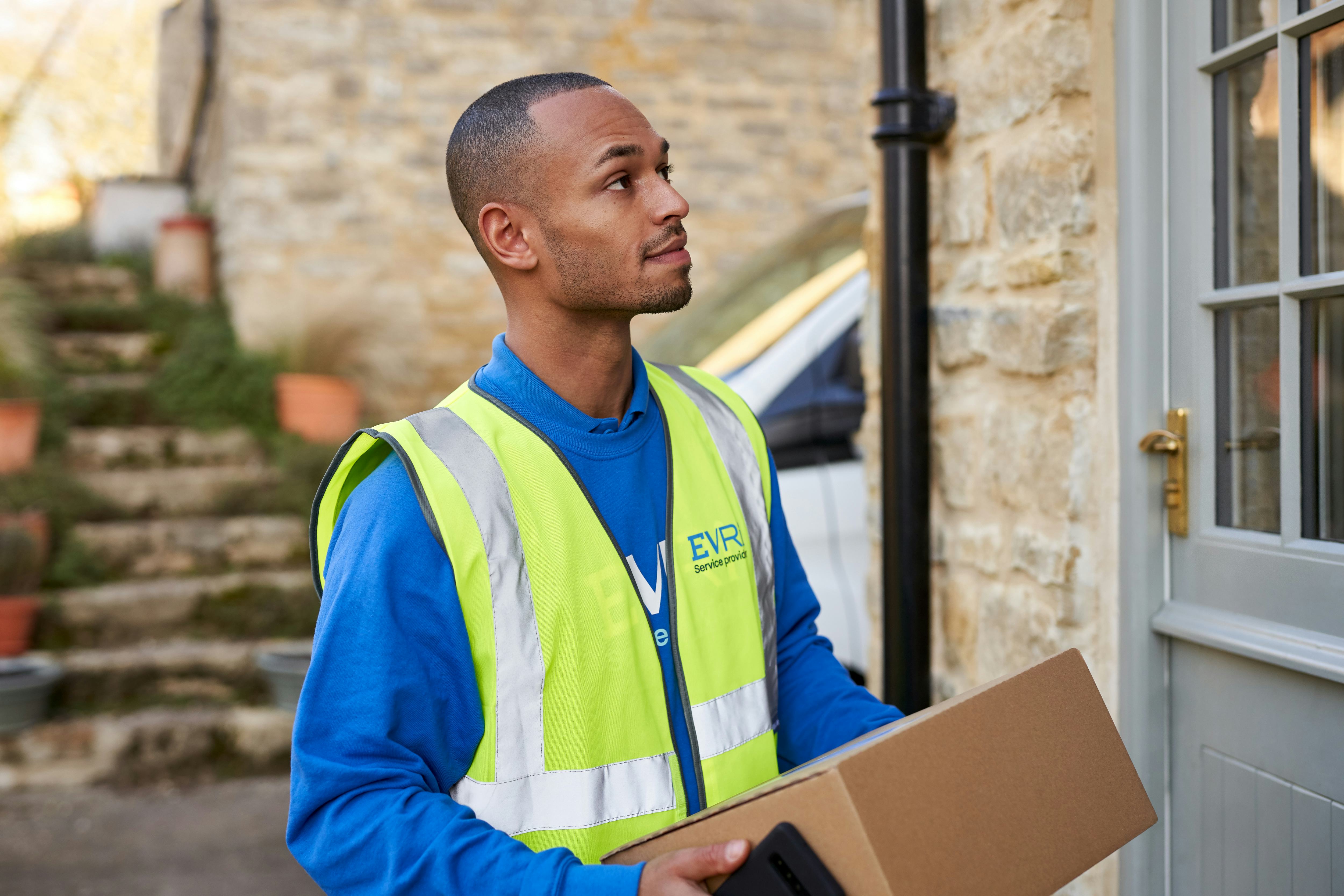 Photo of a courier on doorstep holding parcel box