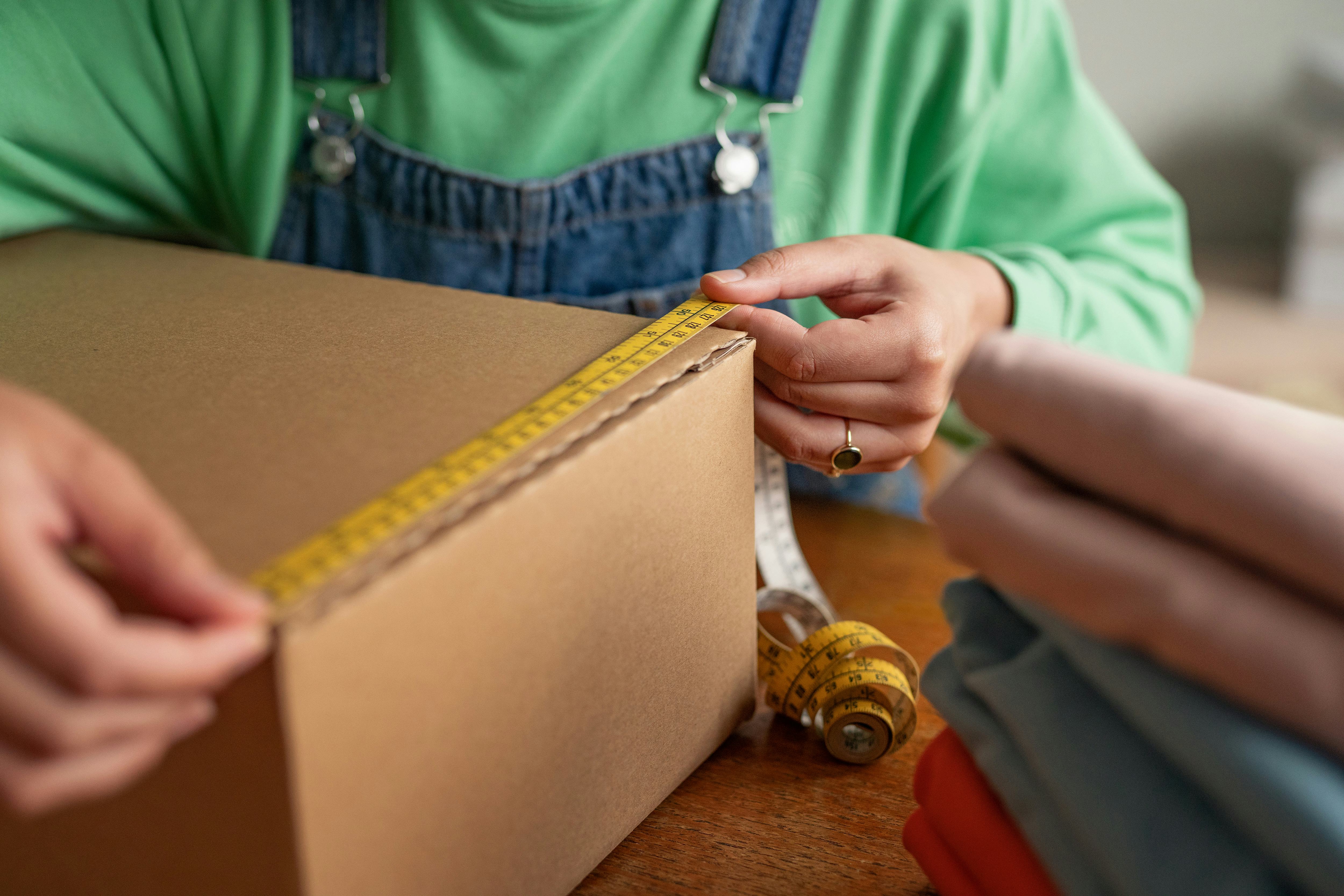 woman holding tape measure against cardboard box on table