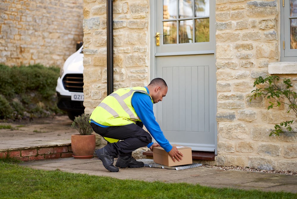 Photo of a courier placing package on doorstep of home
