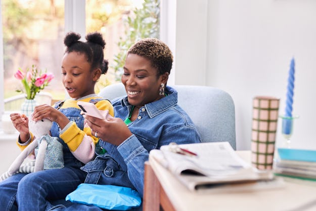 woman sat on sofa with child on lap using  a smartphone