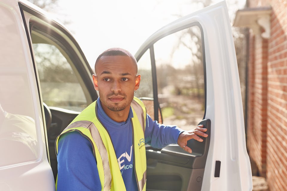 courier in blue uniform exiting white van door