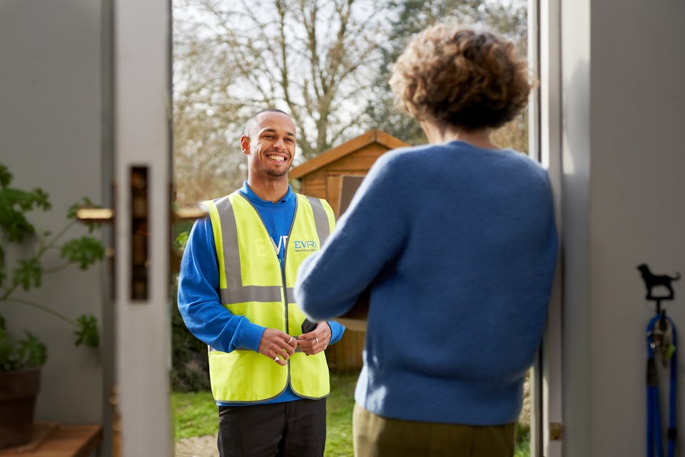 woman answering door to courier in blue uniform