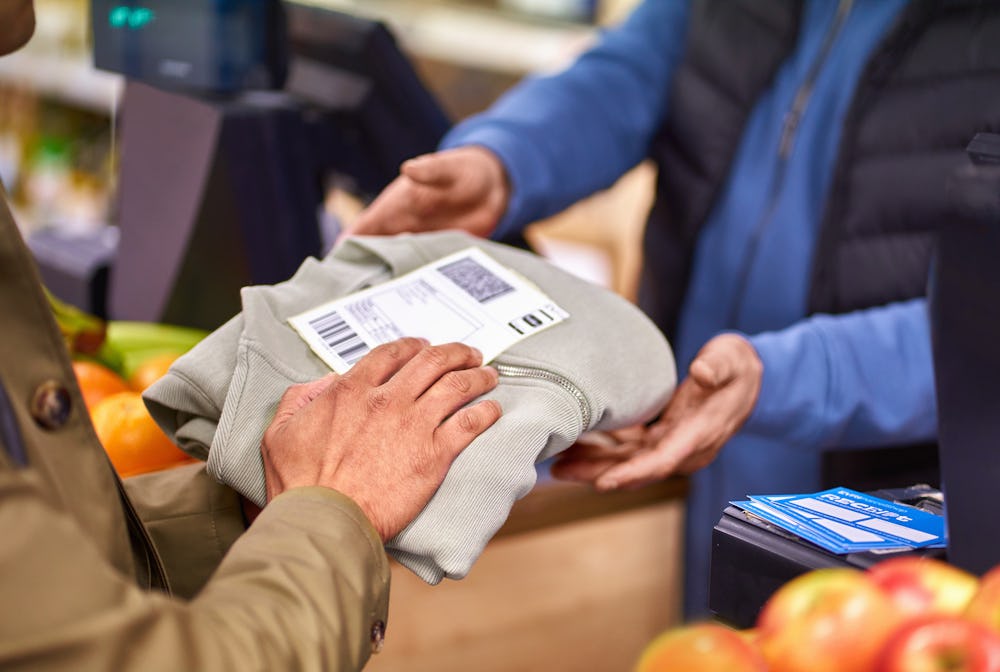 customer handing garment and parcel label to cashier