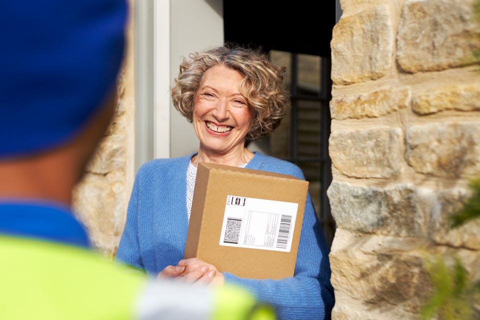 woman at front door holding package and smiling at courier