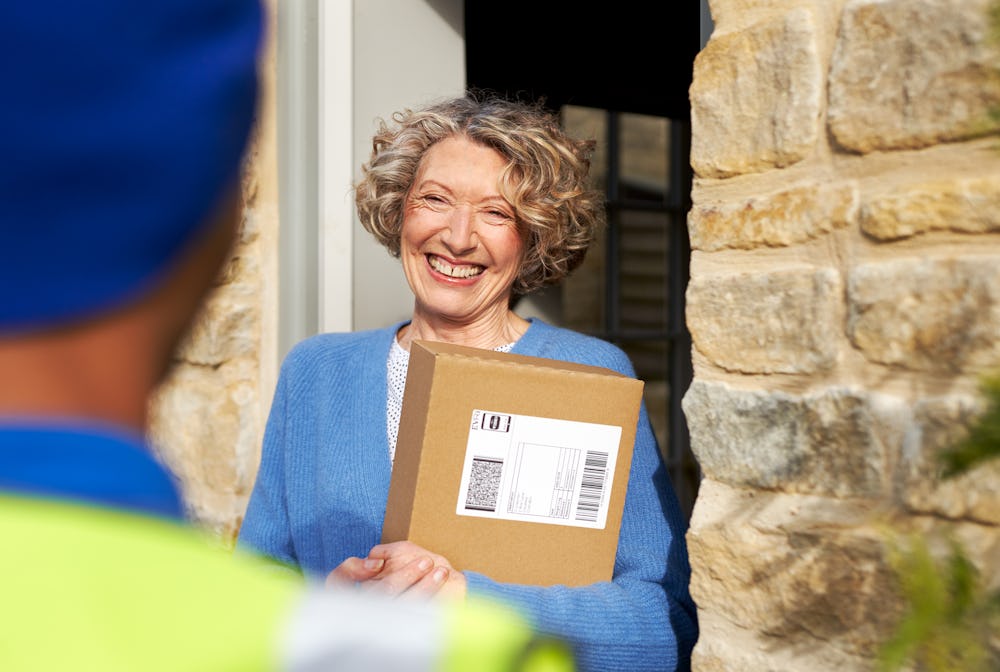 woman at front door holding package and smiling at courier