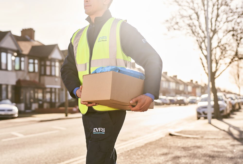 Photo of a courier walking down street holding parcels