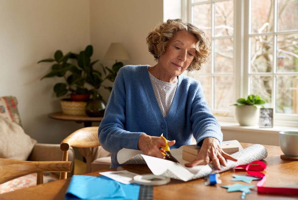 woman at table cutting paper to wrap parcel