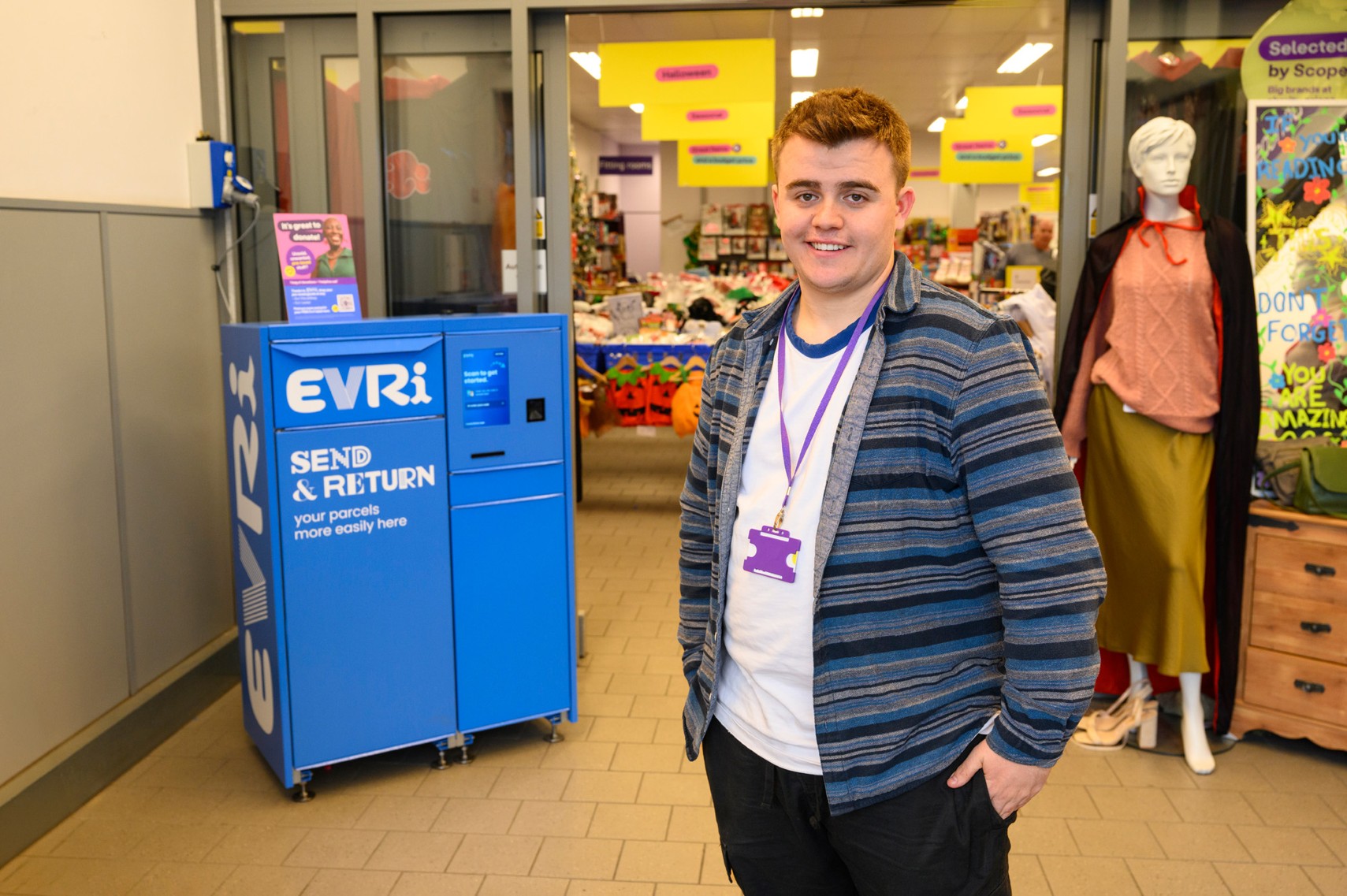 Blue Evri branded parcel locker in Scope's Doncaster charity shop, with Angus, the shop manager stood proudly.