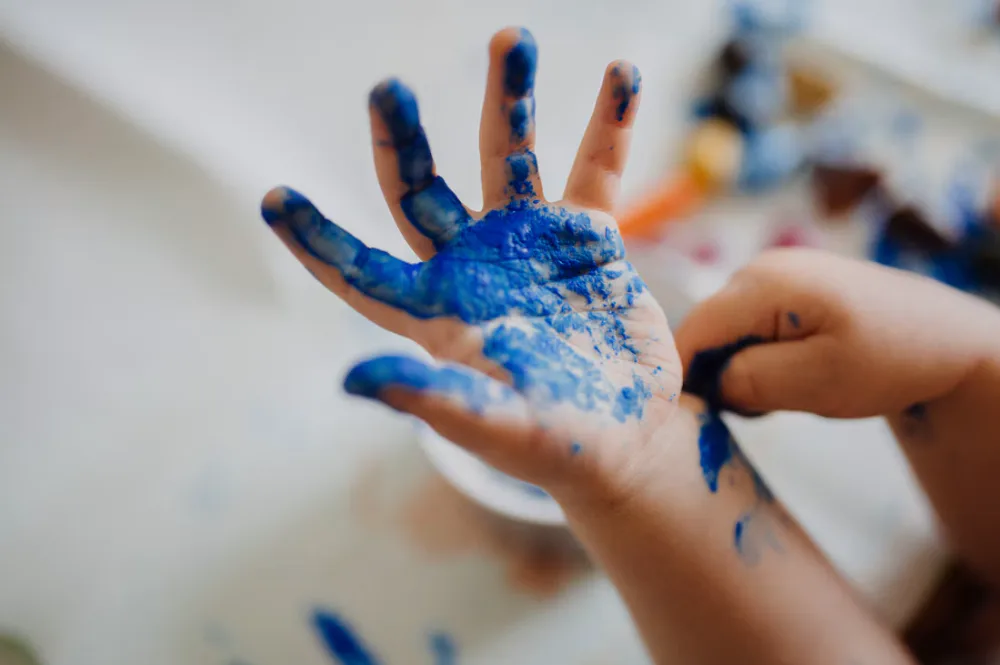 Child with blue paint on hand