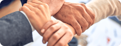 Close up of four hands clasping each other to form a square, symbolizing cohesion