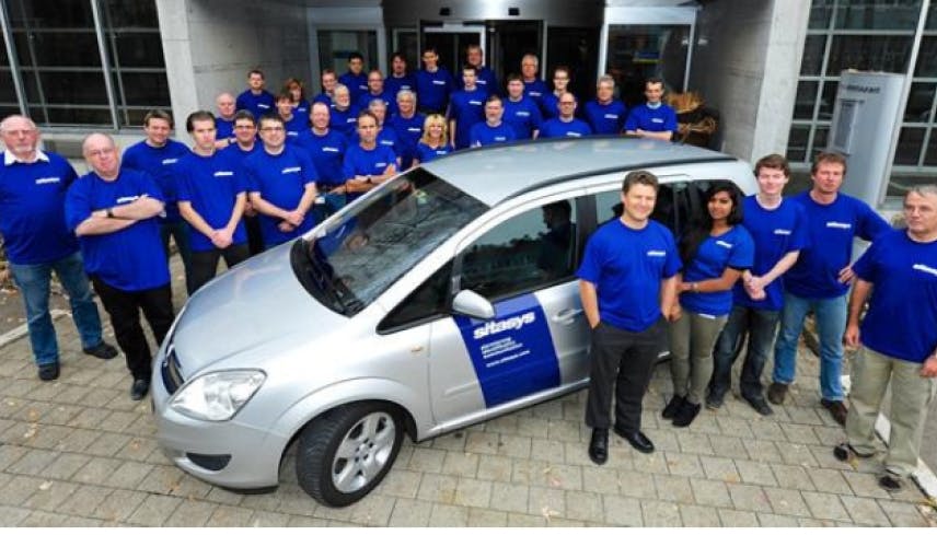 Sitasys team with a car posing outside the office for a team photo 10 years ago