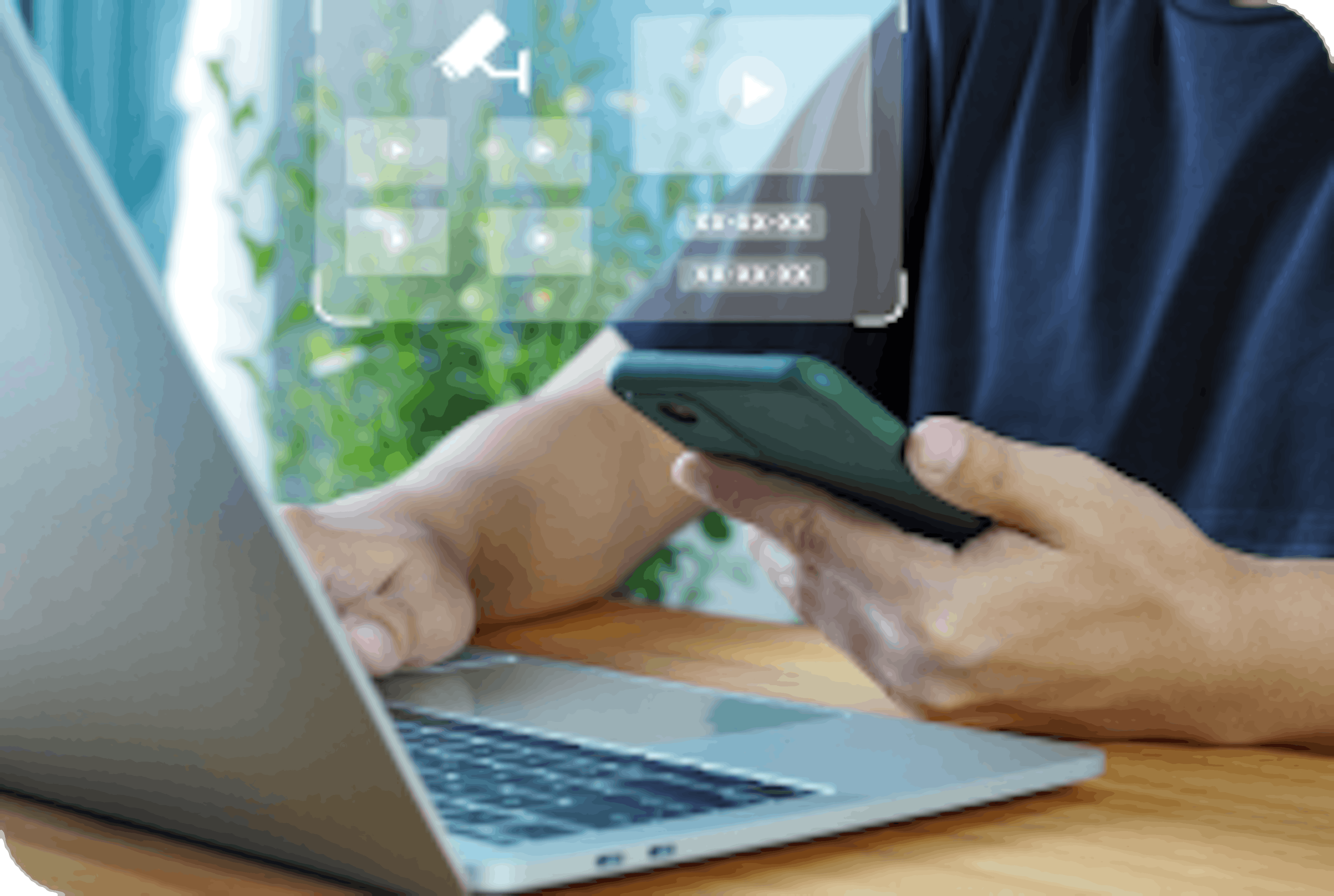 man holding phone and working on laptop to set up camera