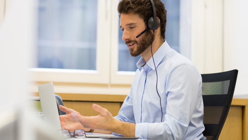 man working on computer and on the phone