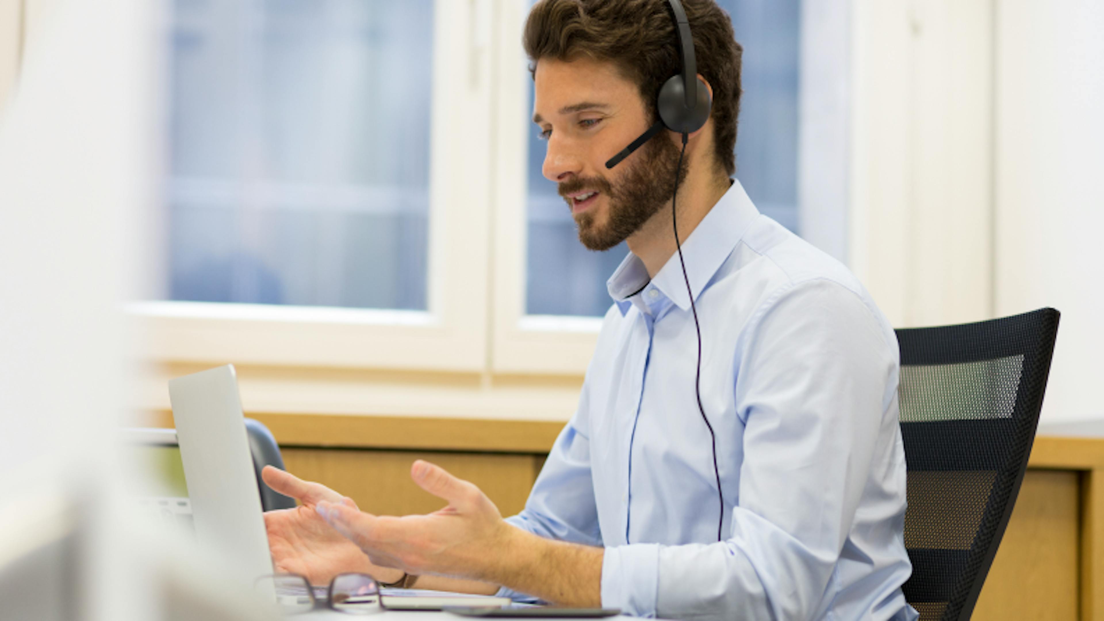 man working on computer and on the phone