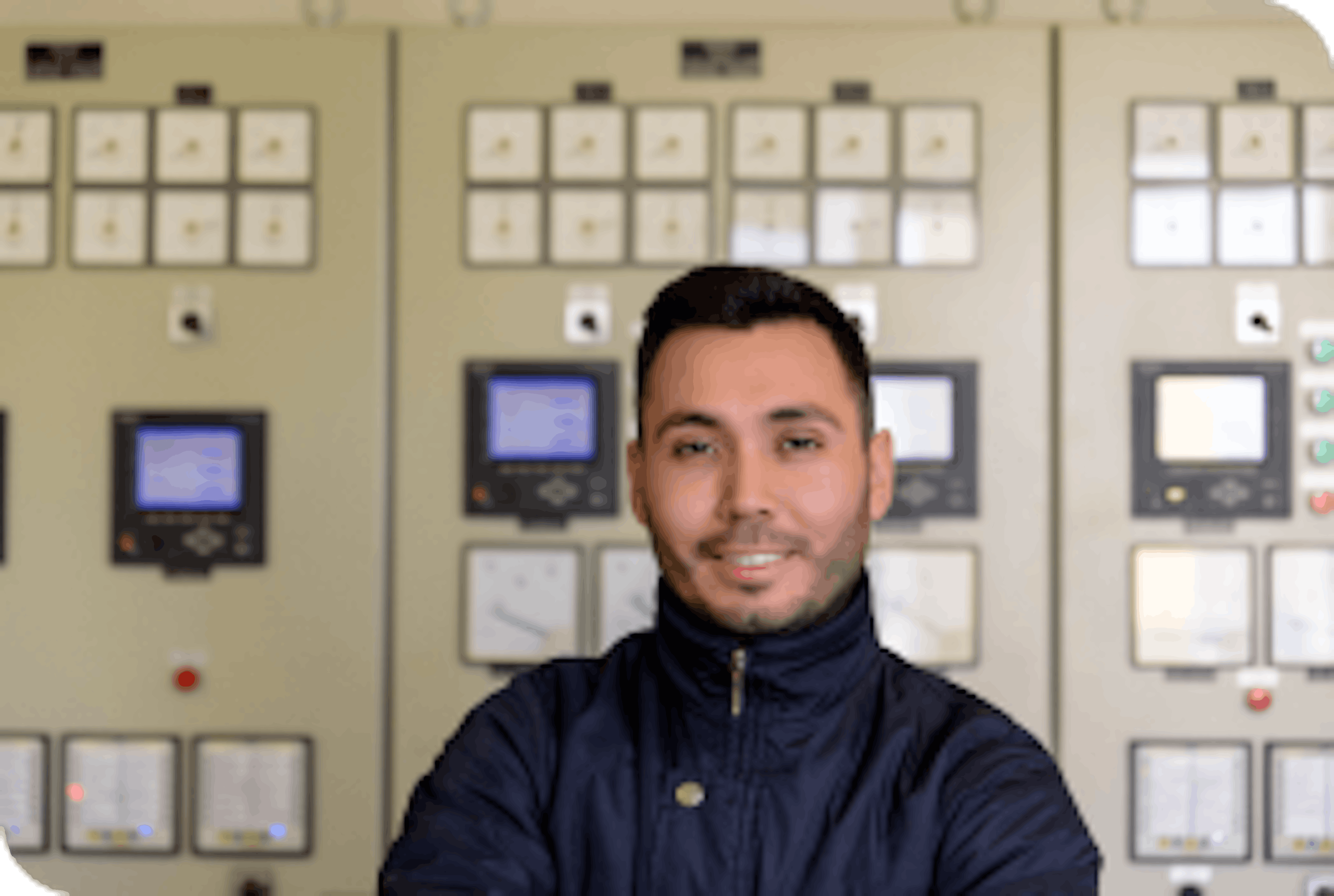 Happy and health SOC operator standing in front of a control panel, smiling